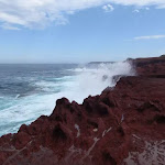Waves crashing onto red cliffs