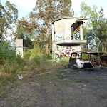 Derelict buildings and a burnt out car at the end of Belmont Lagoon